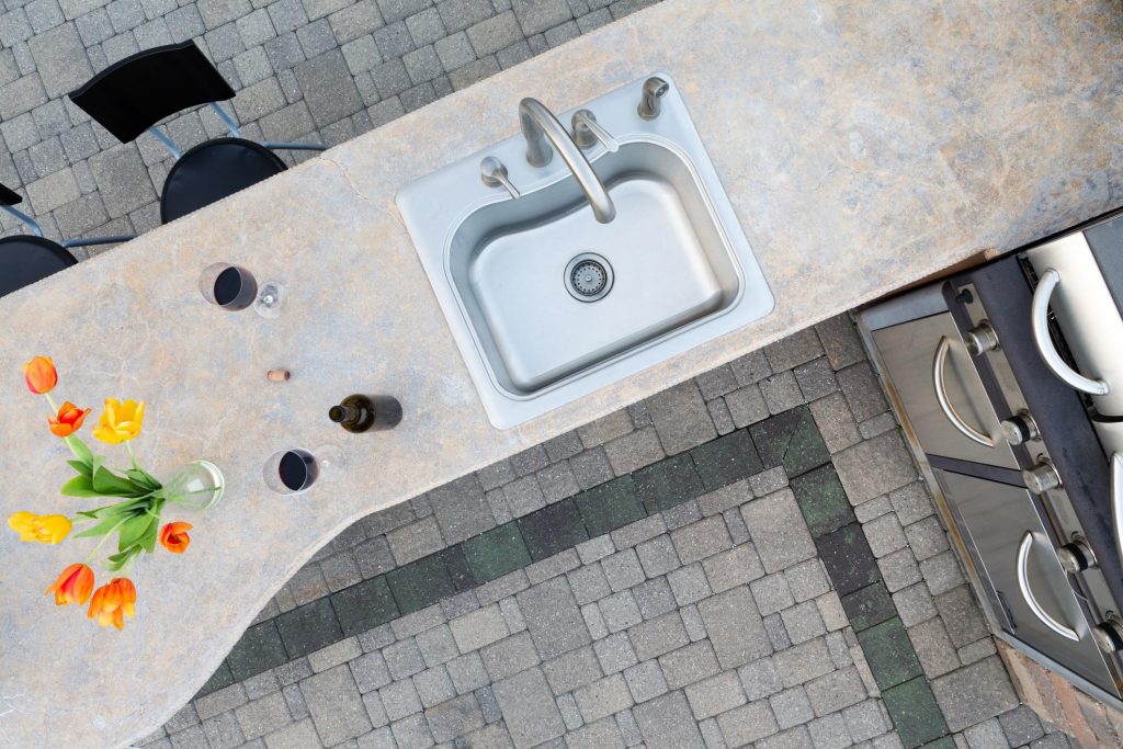 outdoor kitchen with bricked floor and sink outside