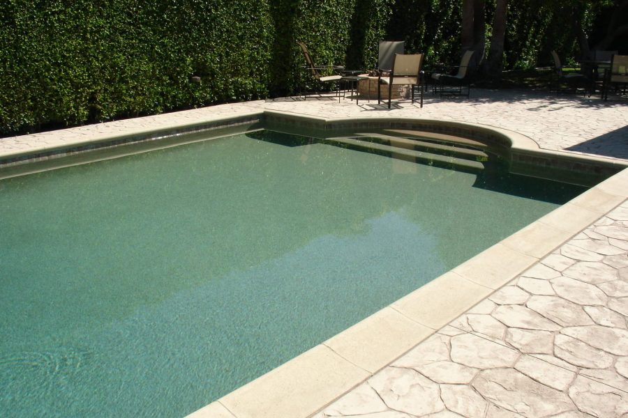 pool filld water with textures floor and surrounded by hedge